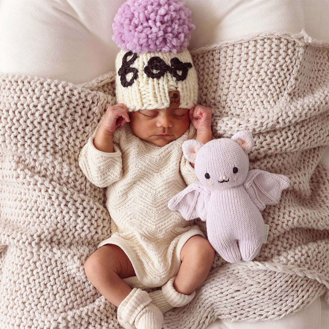 Newborn baby cuddling a lavender knitted baby bat stuffed animal
