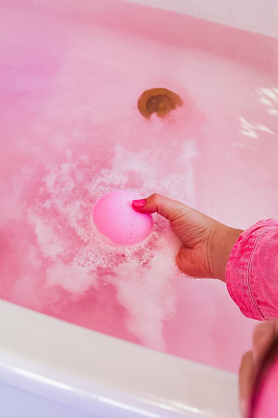 Pink Musee cowgirl-themed bath balm fizzing in a tub of water. 