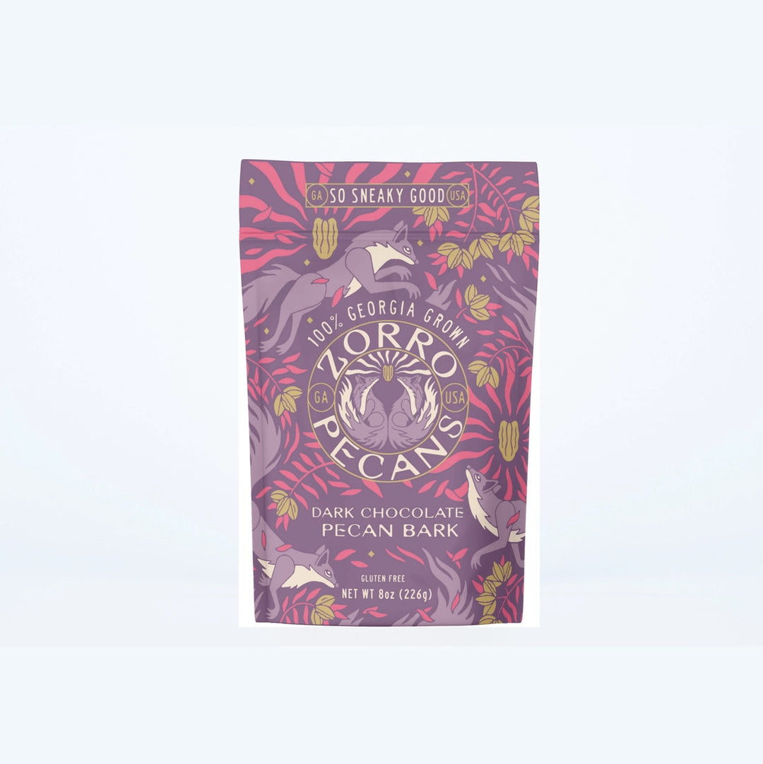 Zorro Dark Chocolate Pecan Bark in decorative purple and pink packaging featuring Georgia-grown pecans and whimsical squirrel artwork.