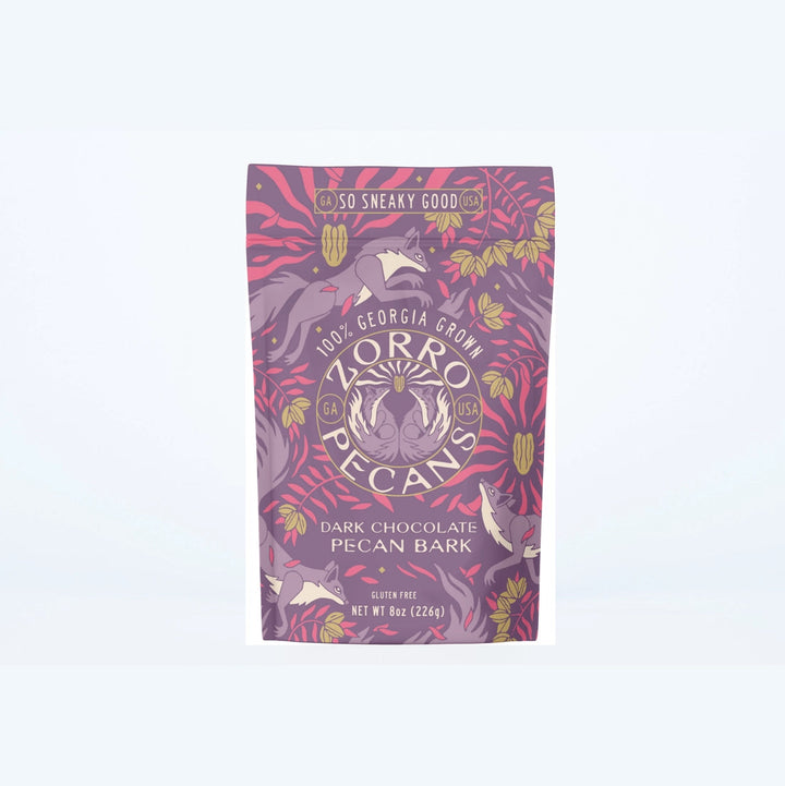 Zorro Dark Chocolate Pecan Bark in decorative purple and pink packaging featuring Georgia-grown pecans and whimsical squirrel artwork.