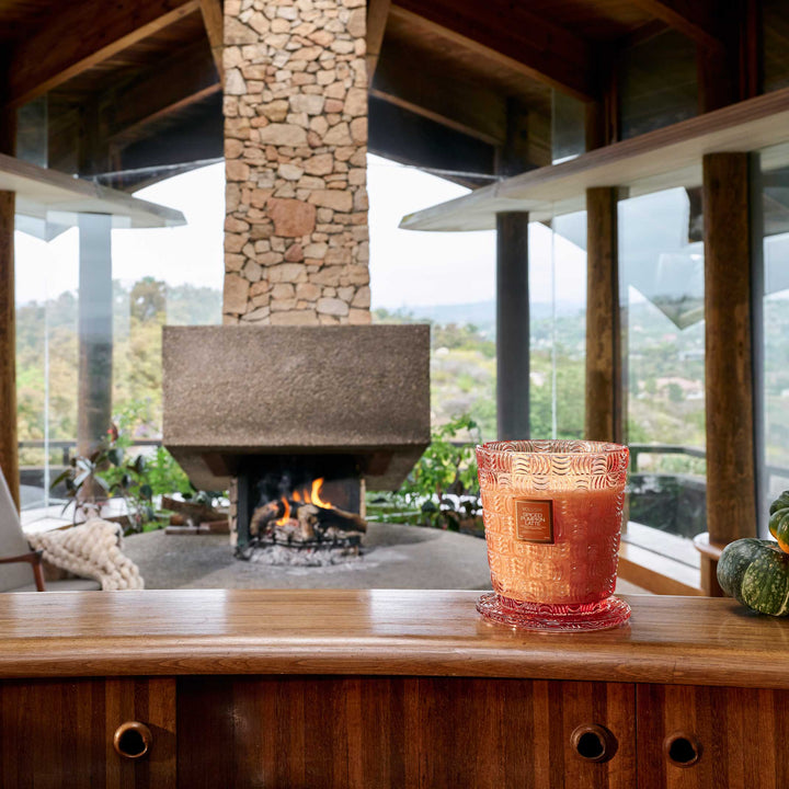 Voluspa Spiced Pumpkin Latte 5 Wick Hearth Candle displayed in a cozy fall interior near a fireplace