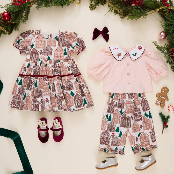 Pink Chicken Baby Girls Noelle 2PC Set displayed alongside the matching Eliza Gingerbread Houses Dress with festive Christmas accessories.