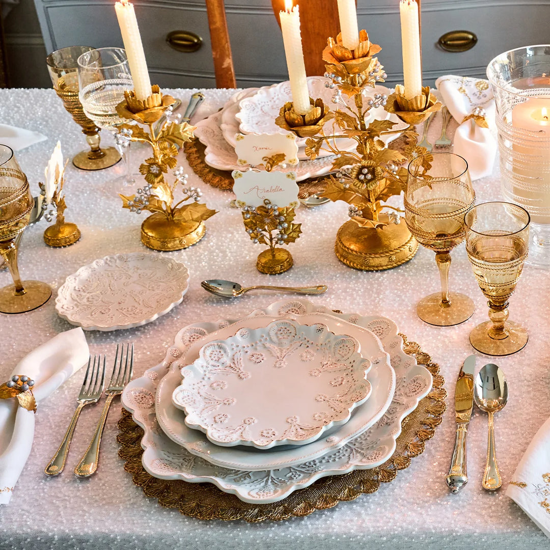 Amber gold stemmed wine glasses displayed on an elegant formal tablescape with white dinnerware and gold accents