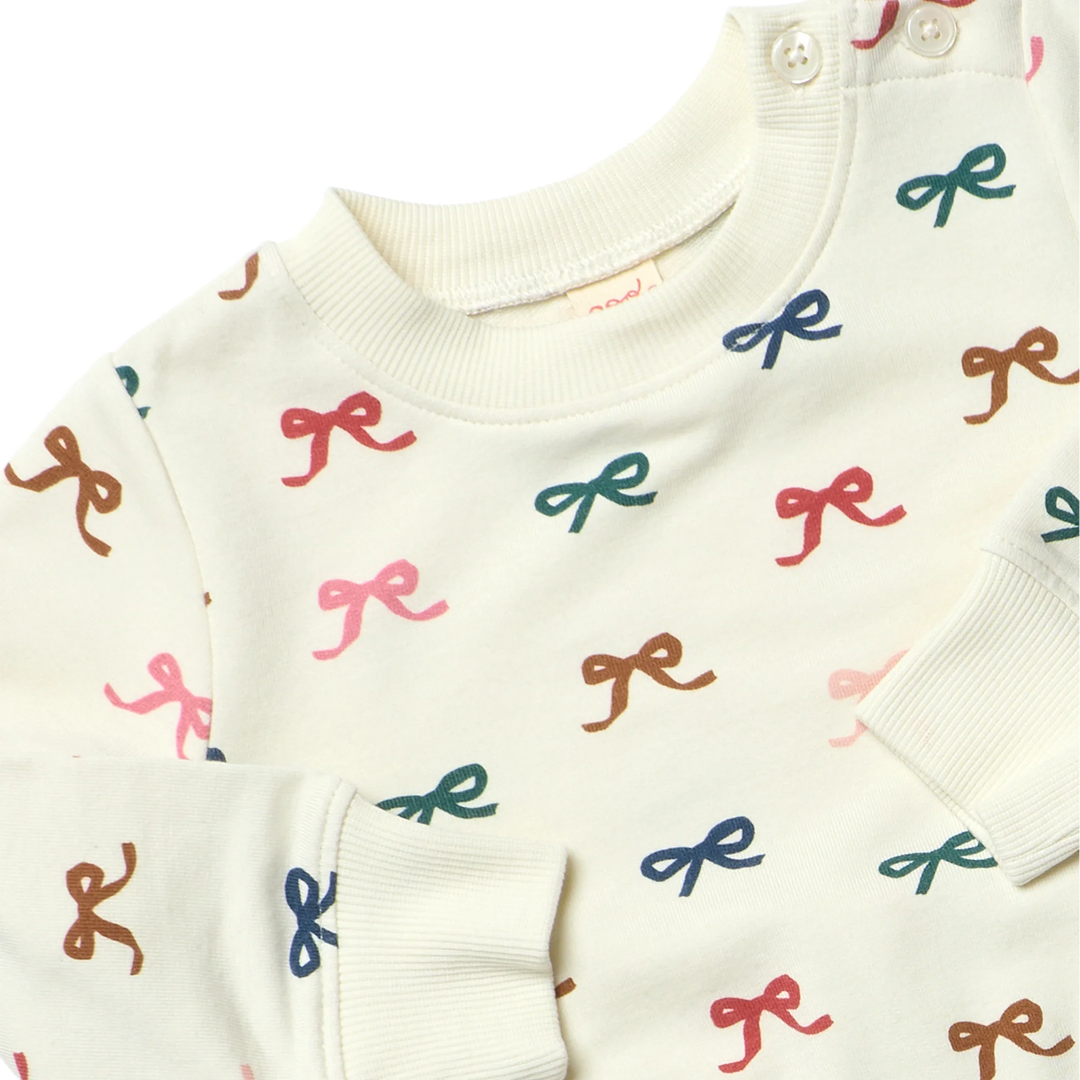 Close-up of cream Baby Bow Jogger Set showing colorful pink, blue, green, red and brown bows with ribbed trim