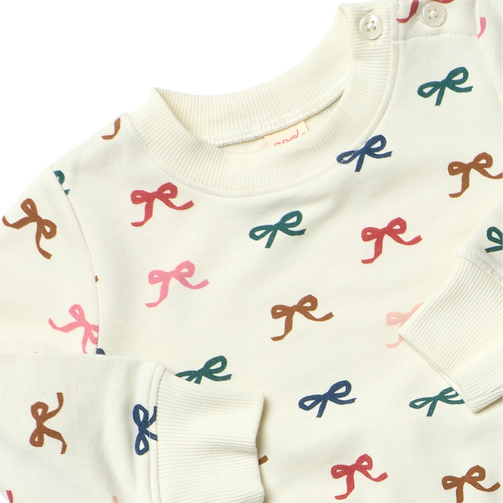 Close-up of cream Baby Bow Jogger Set showing colorful pink, blue, green, red and brown bows with ribbed trim