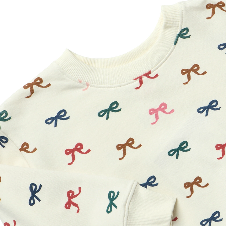 Close-up of cream Baby Bow Romper showing the multicolor bow print, soft fabric and ribbed neckline and cuff