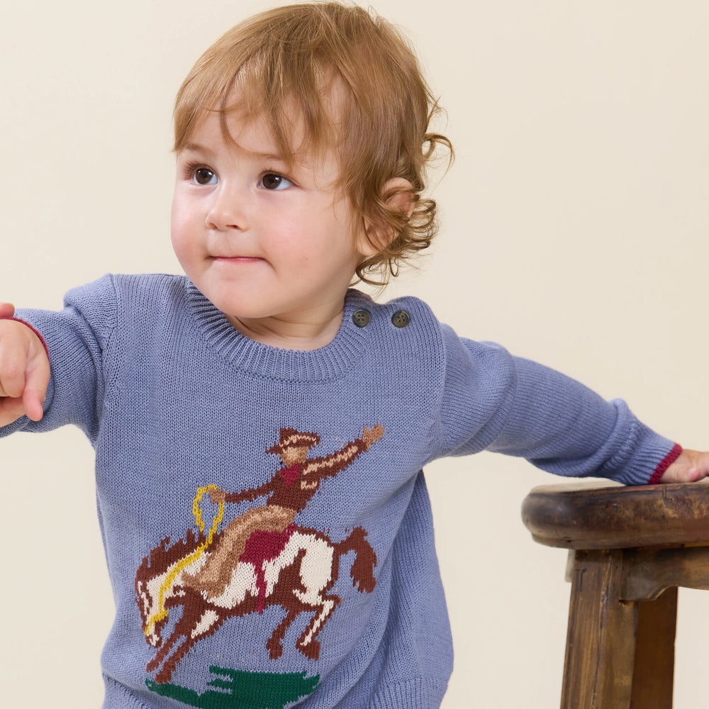 Baby boy wearing blue Bronco Sweater with cowboy and bucking horse design