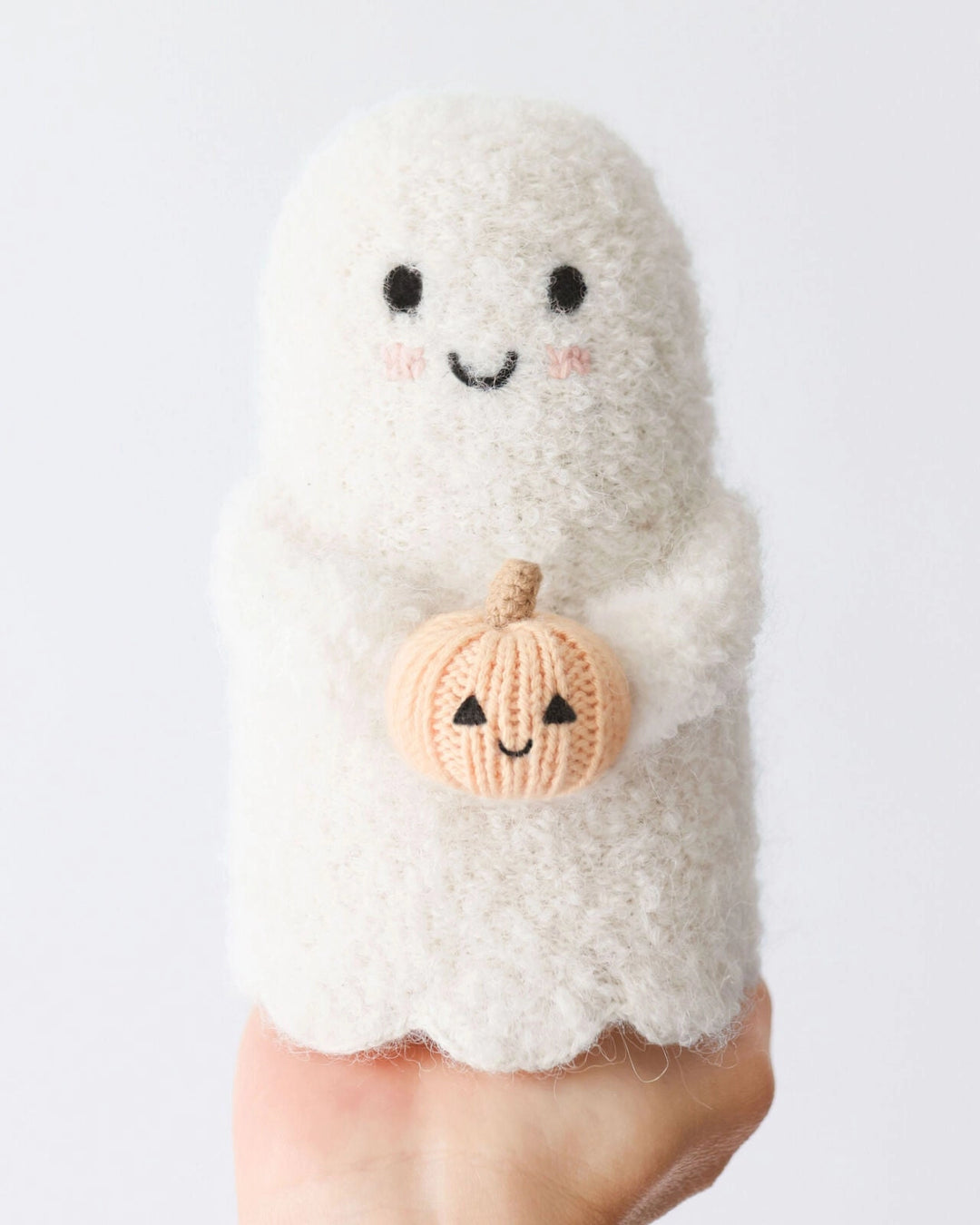 Hand holding the Baby Ghost with Pumpkin to show its size and soft knit design