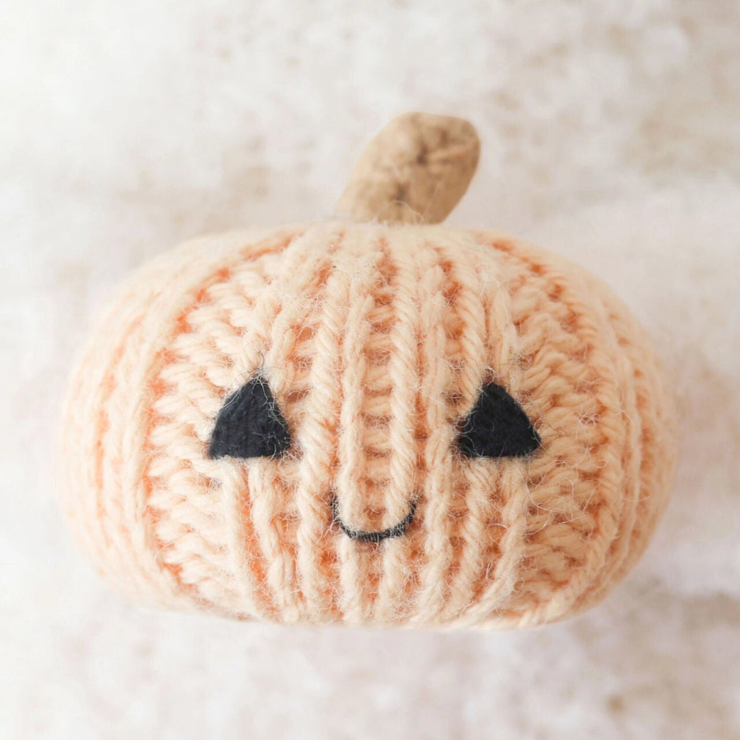 Close-up of the smiling peach knit pumpkin held by the Baby Ghost toy