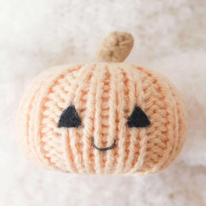 Close-up of the smiling peach knit pumpkin held by the Baby Ghost toy