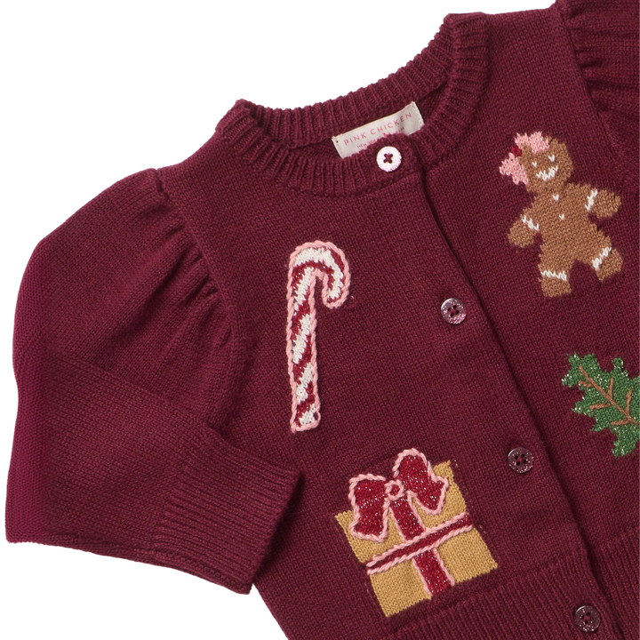 Close-up of Baby Girls Constance Sweater showing holiday patches, textured burgundy knit, puff sleeves, and button-front details.