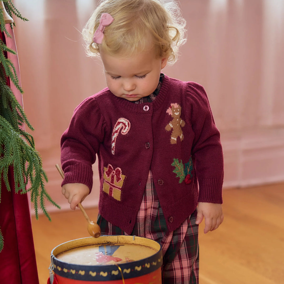 Toddler wearing the Pink Chicken Holiday Patches Constance Sweater layered over a burgundy tartan holiday outfit.
