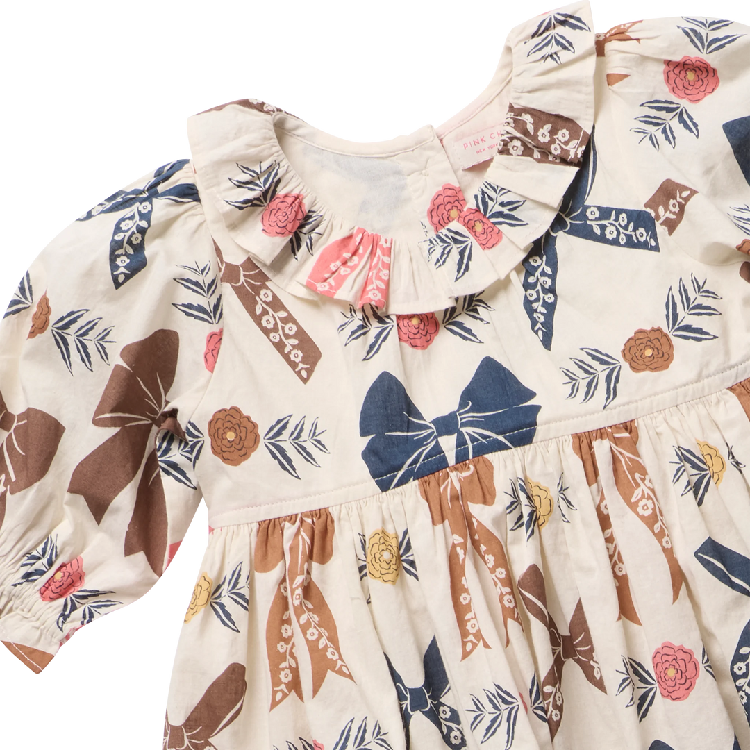 Close-up of Baby Girls Harvest Bow Dress Set featuring ruffled collar and navy, brown and pink bow print