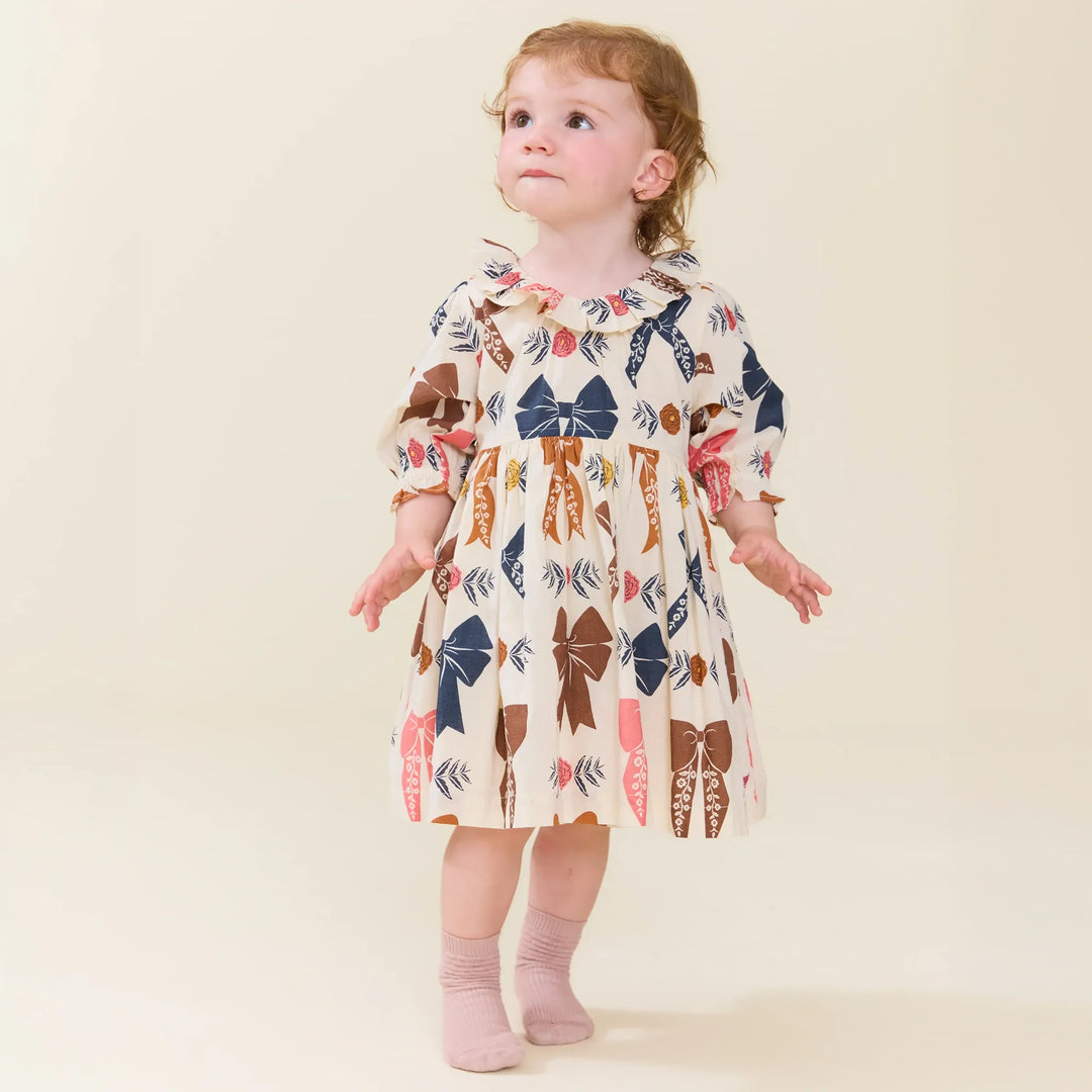 Baby girl wearing Baby Girls Harvest Bow Dress Set with ruffled collar and colorful fall bow print