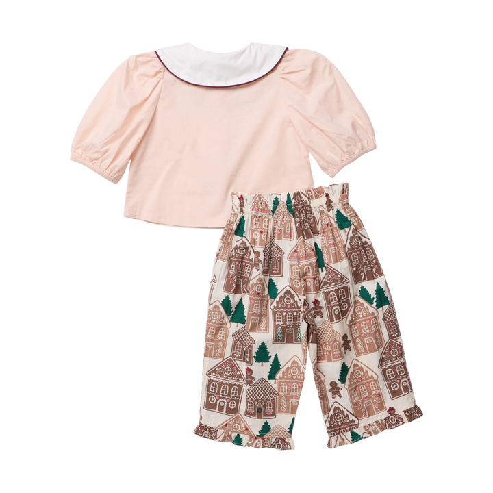 Back view of the Pink Chicken Baby Girls Noelle 2PC Set featuring a blush pink puff sleeve top and gingerbread house print pants with ruffled hems.