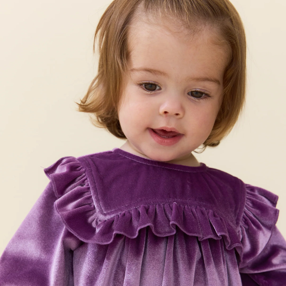 Baby girl modeling the lavender velour Quinn Bubble with statement ruffle detailing