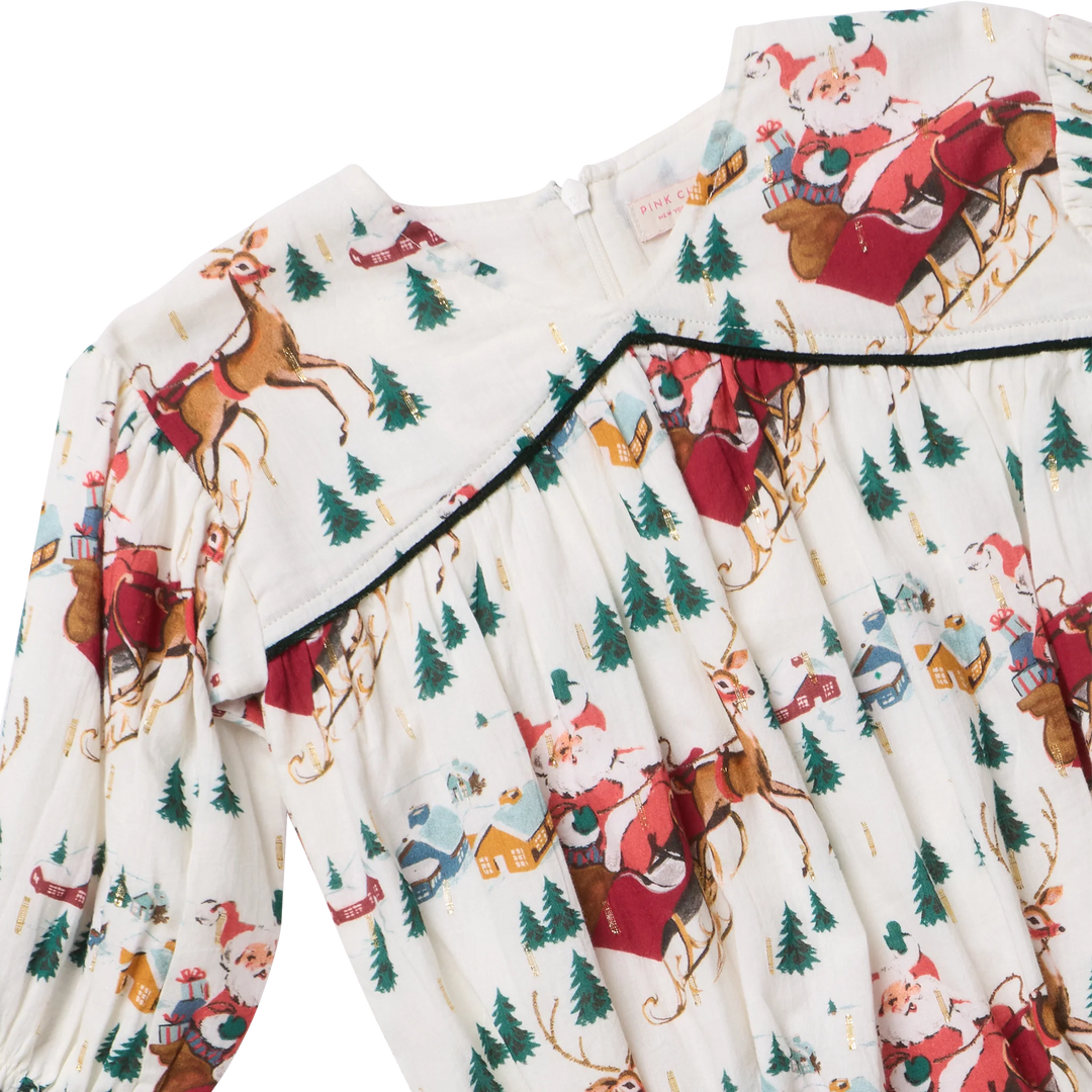 Close-up of Wynne Bubble featuring Santa and reindeer print, delicate gold accents, and dark green piping