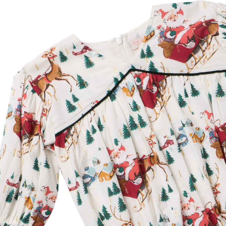 Close-up of Wynne Bubble featuring Santa and reindeer print, delicate gold accents, and dark green piping
