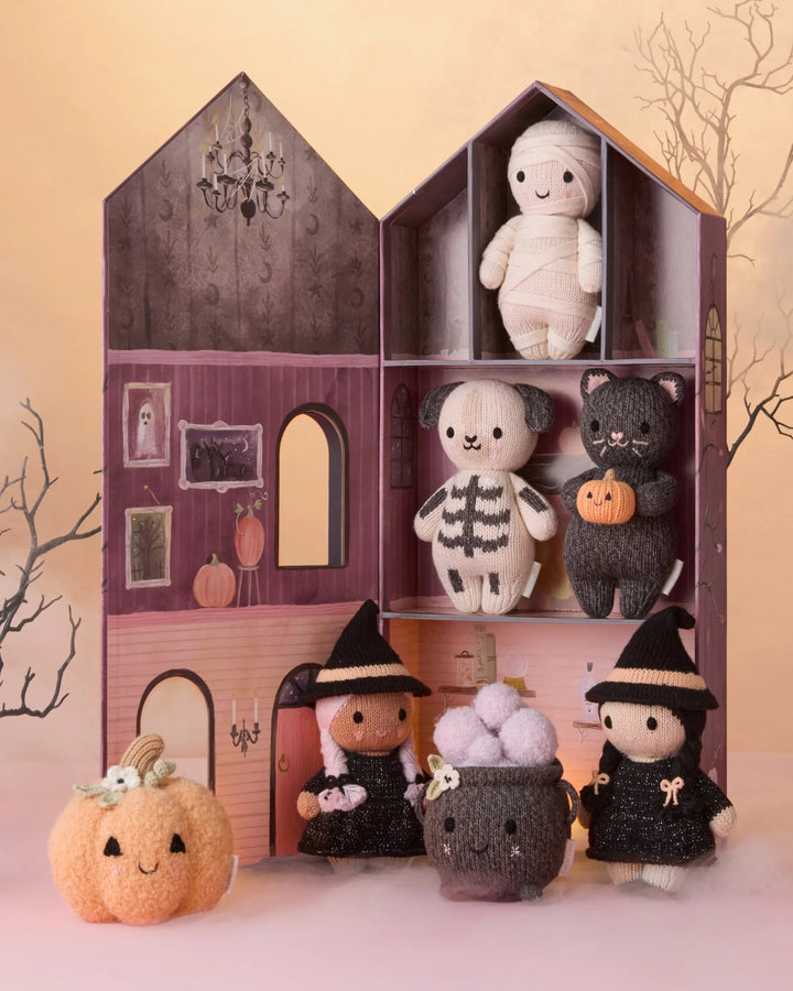 Baby Pumpkin Moonflower plush displayed with knit Halloween characters in a whimsical haunted house scene