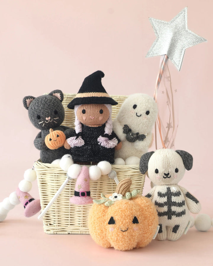 Baby Pumpkin Moonflower plush with knit Halloween characters arranged around a whimsical gift basket