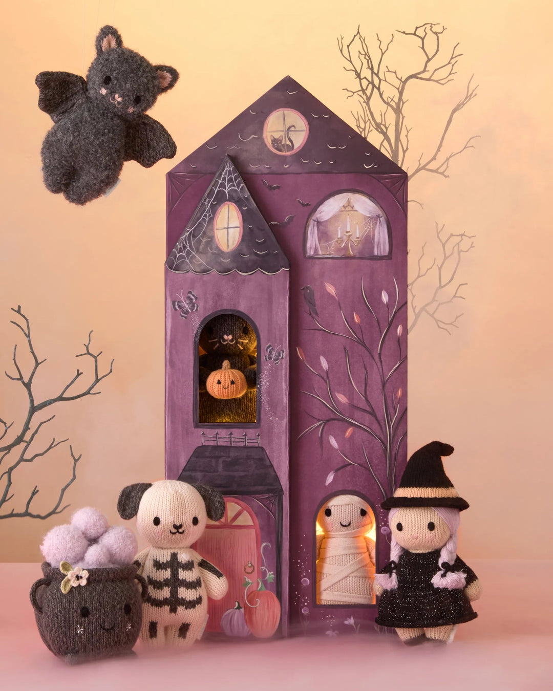 Baby Pumpkin Moonflower plush featured with knit Halloween characters and a whimsical purple haunted house display