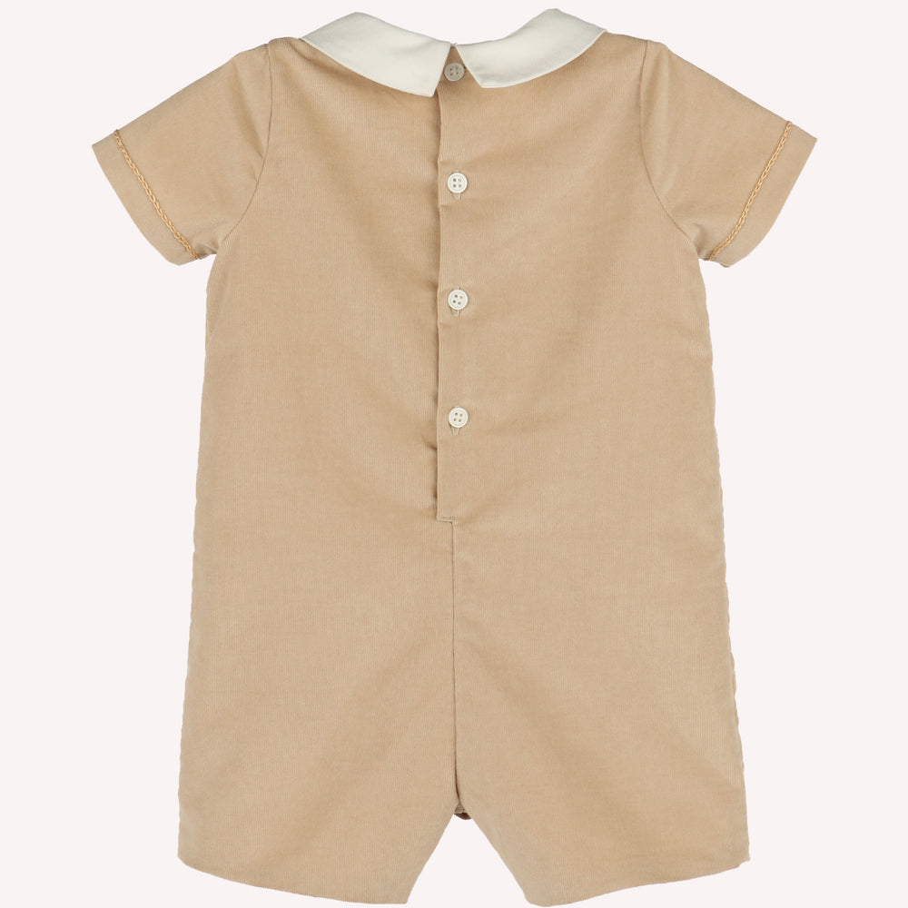 Back view of beige corduroy baby boy romper with ivory Peter Pan collar, short sleeves, and button-back closure.