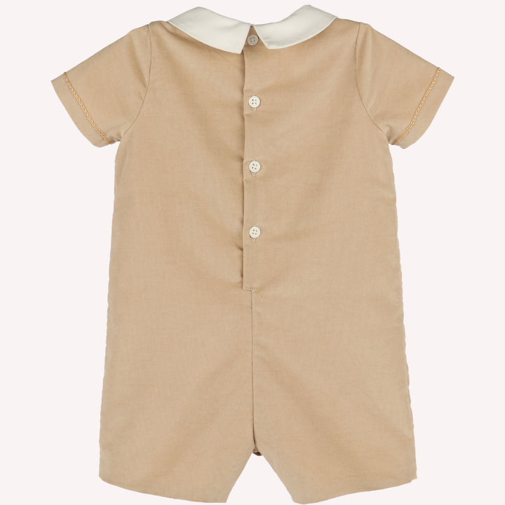 Back view of beige corduroy baby boy romper with ivory Peter Pan collar, short sleeves, and button-back closure.