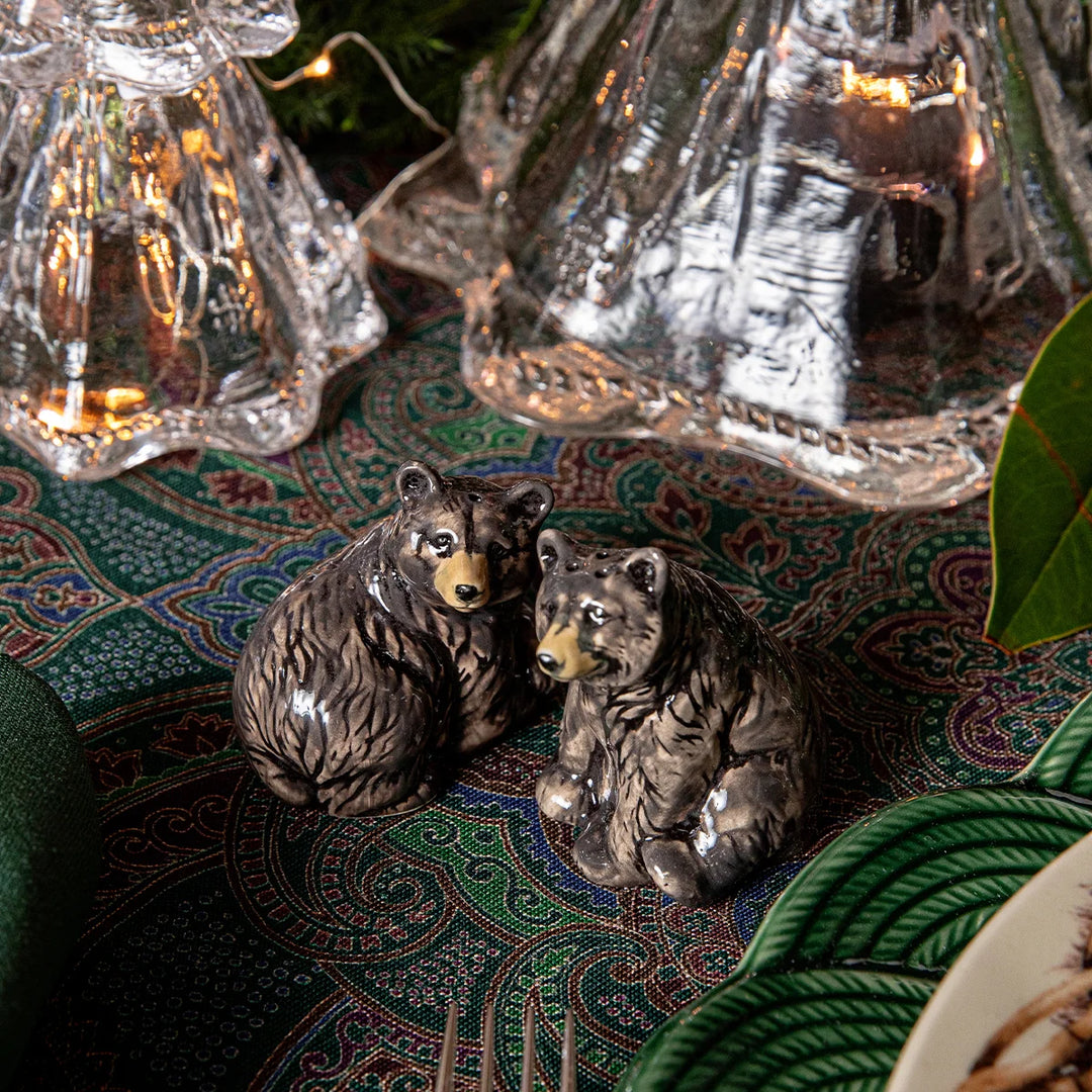 Black bear figurines styled on a green paisley Christmas table with glass trees for a woodland holiday tablescape.