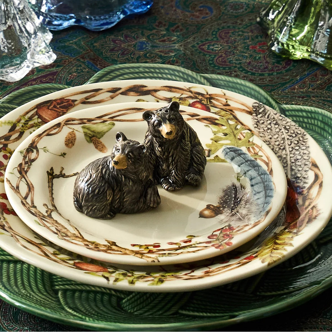 Pair of black bear figurines displayed on botanical dinnerware in an elegant woodland-inspired table setting.