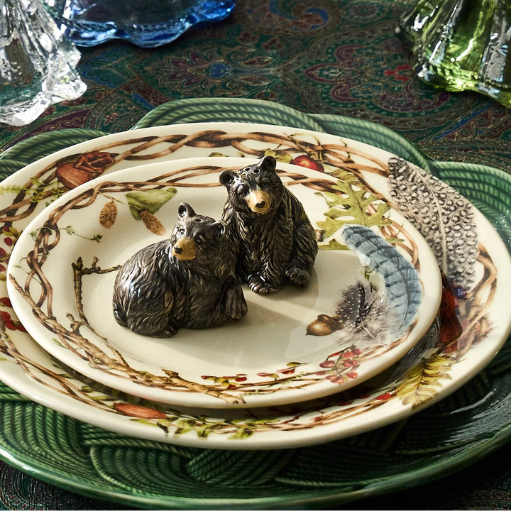 Pair of black bear figurines displayed on botanical dinnerware in an elegant woodland-inspired table setting.