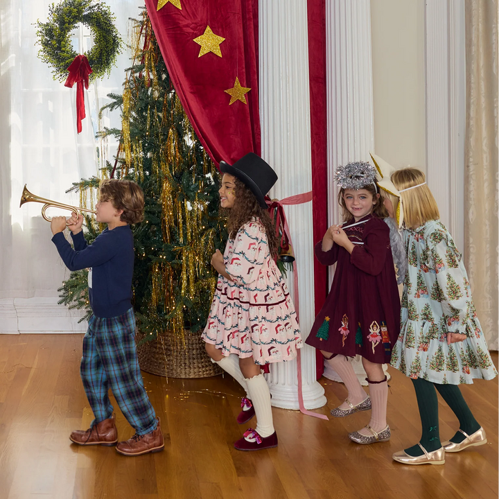 Boy wearing Pink Chicken Blue Tartan Jackson Pants while playing a trumpet during a festive Christmas gathering