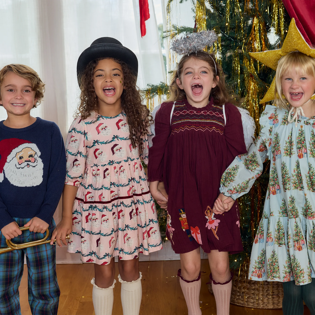 Boy wearing Pink Chicken Boys Oliver Sweater Navy Santa alongside children in festive Christmas outfits