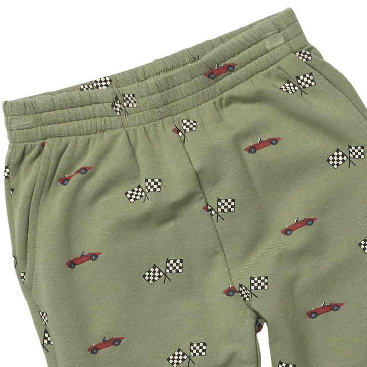 Close-up of boys race car jogger pants showing red race cars, checkered racing flags, elastic waistband and pocket