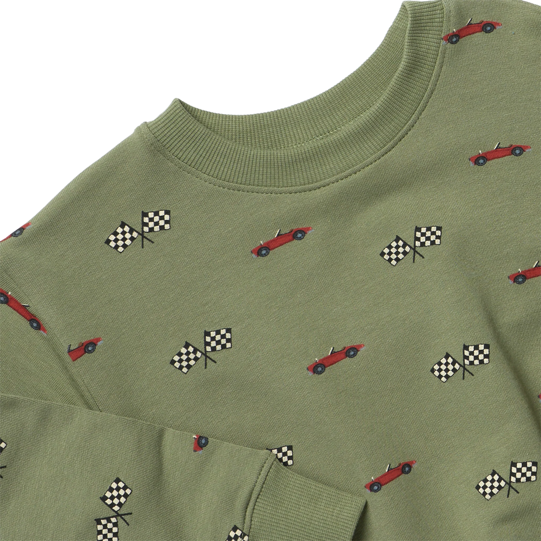 Close-up of olive green boys race car sweatshirt showing red cars, black-and-white checkered flags, and ribbed crew neckline.