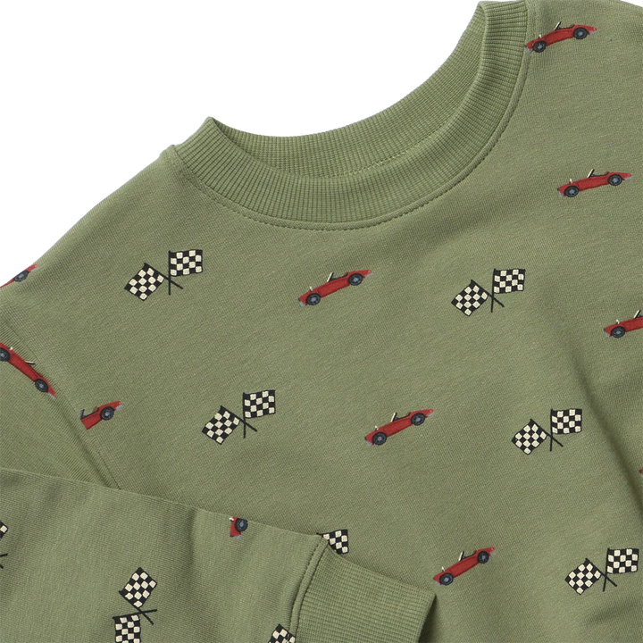 Close-up of olive green boys race car sweatshirt showing red cars, black-and-white checkered flags, and ribbed crew neckline.