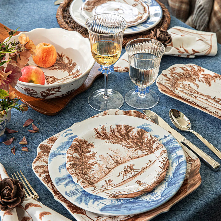 Brown toile serving bowl styled with coordinating brown and blue toile plates, glassware and table linens
