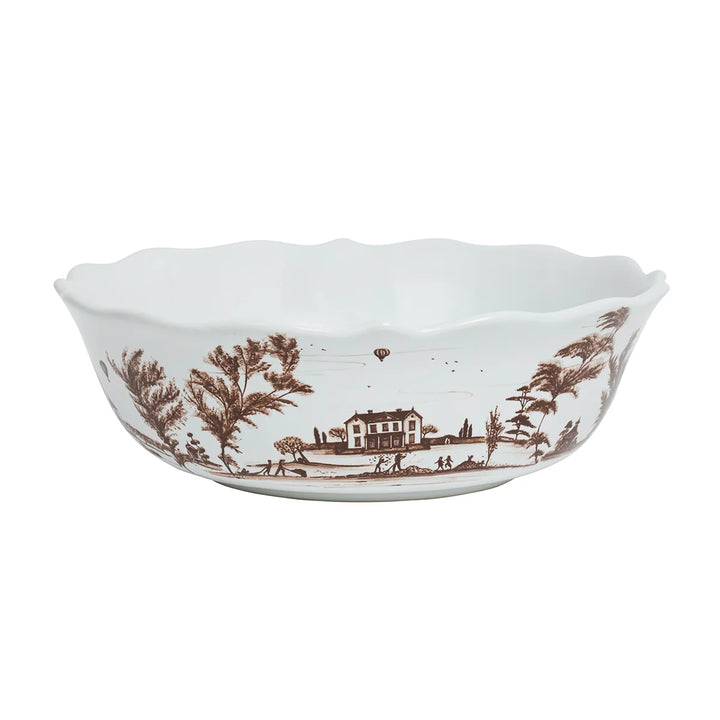 Brown toile serving bowl with white ceramic finish, scalloped rim and detailed pastoral landscape scene
