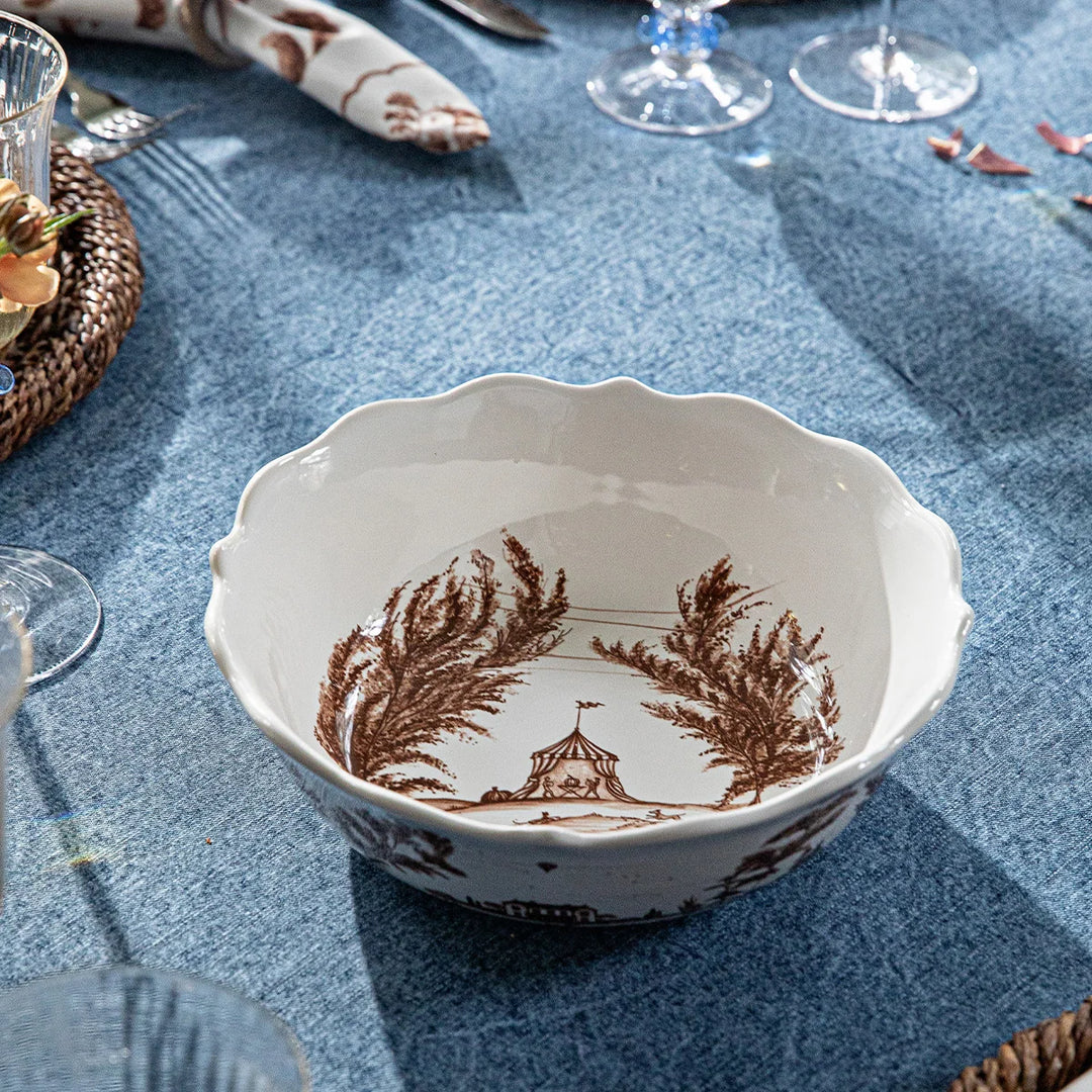 Brown toile serving bowl displayed on an elegant blue table setting with coordinating toile dinnerware