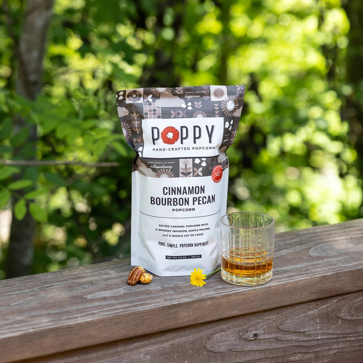 Poppy Cinnamon Bourbon Pecan Popcorn displayed outdoors with a glass of bourbon