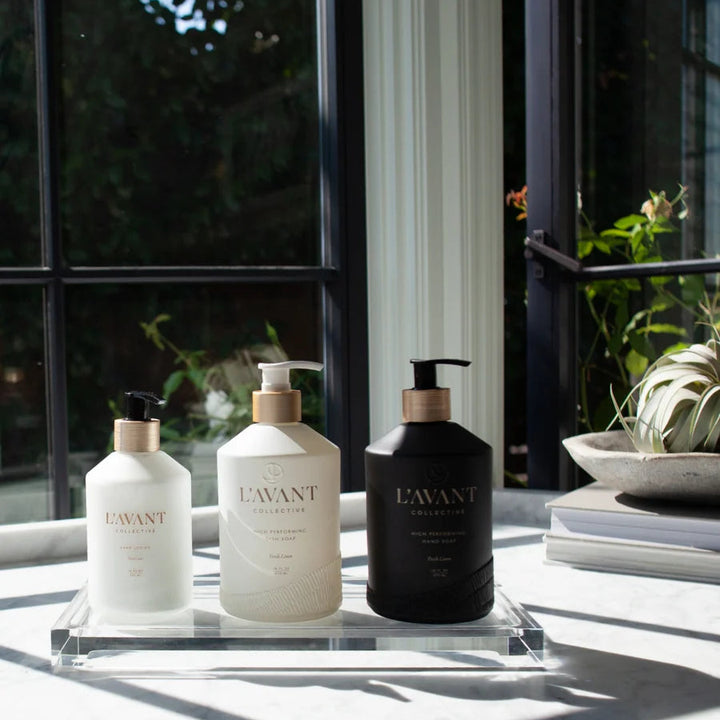 Clear acrylic lucite tray displaying hand lotion, dish soap, and hand soap on a bright countertop for modern sink-side organization.