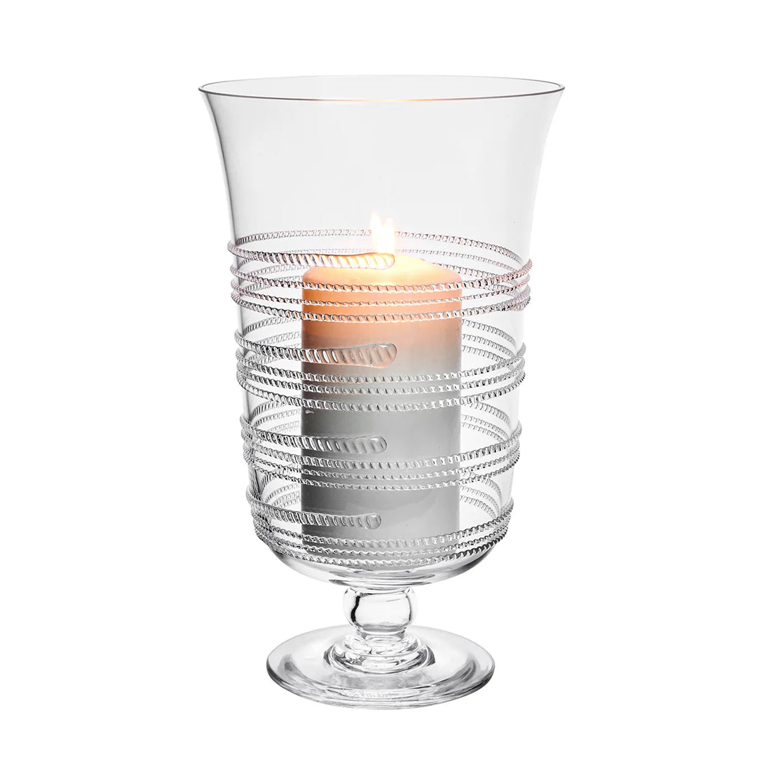 Clear footed glass hurricane candle holder with textured glass bands and an ivory pillar candle