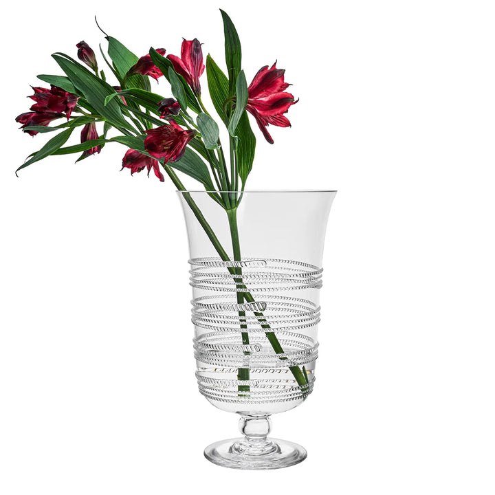 Clear glass hurricane vase with decorative wrapped detailing filled with red flowers and greenery