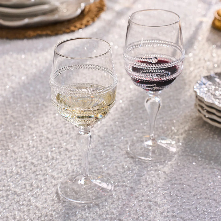 Clear textured wine glasses filled with red and white wine on an elegant dining table