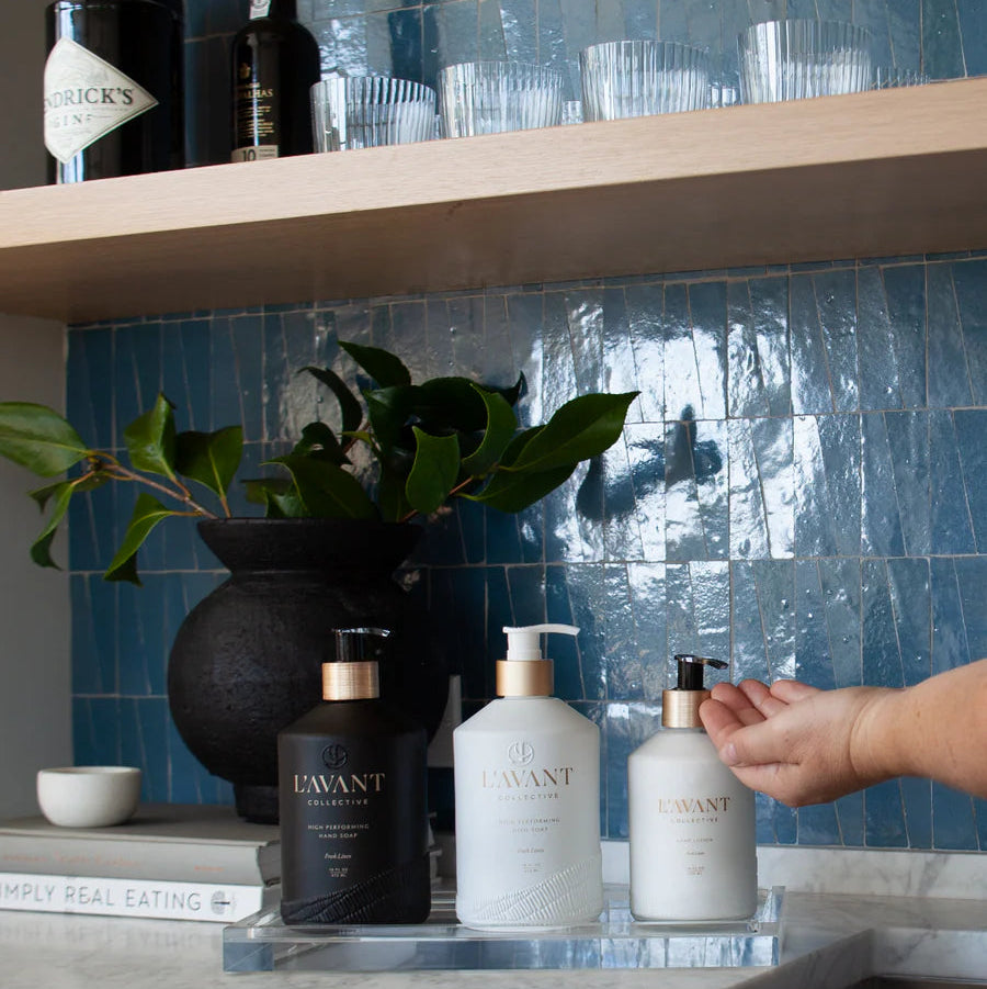 Clear lucite countertop tray styled with hand soap, dish soap, and hand lotion for an elegant kitchen sink organization display.