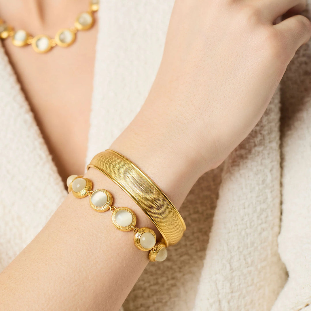 Gold Cobblestone Hinge Bangle styled on wrist with gemstone bracelet