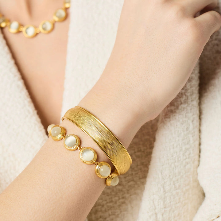 Gold Cobblestone Hinge Bangle styled on wrist with gemstone bracelet