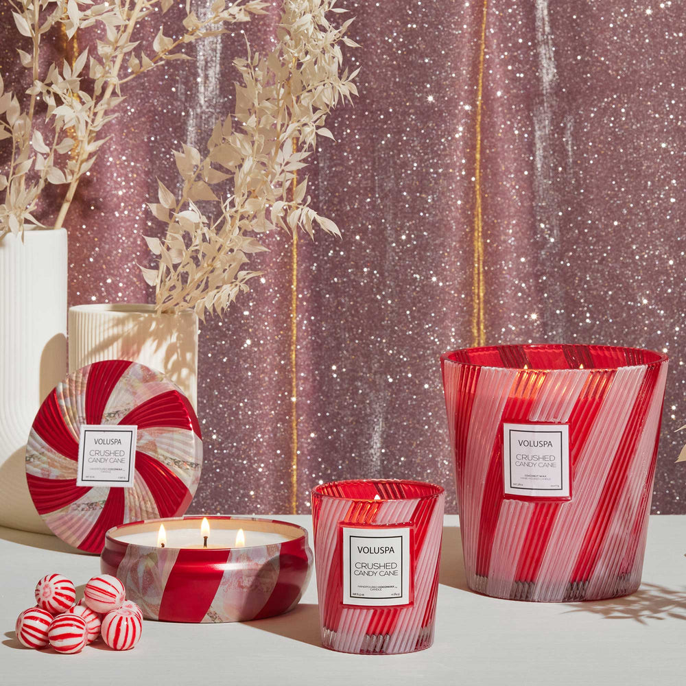 Crushed Candy Cane 3 Wick Hearth Candle displayed with coordinating Voluspa holiday candles and peppermint candies