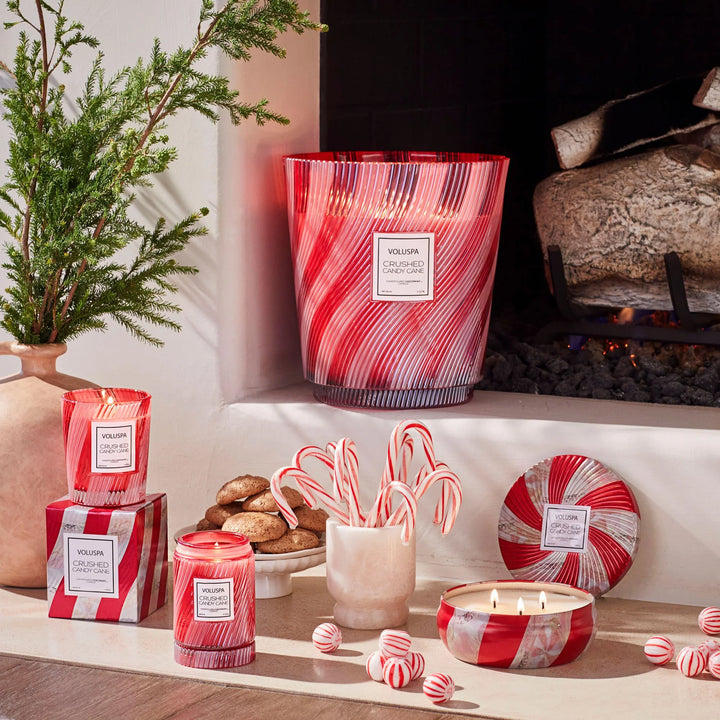 Voluspa Crushed Candy Cane 5 Wick Hearth Candle styled by a fireplace with candy canes and coordinating holiday candles