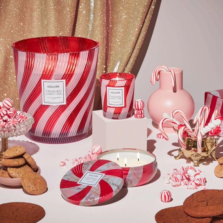 Voluspa Crushed Candy Cane Classic Candle displayed with peppermint candy canes and coordinating Christmas candles