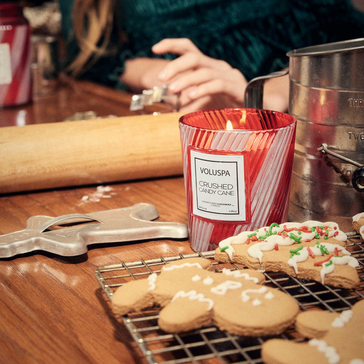 Crushed Candy Cane Classic Candle burning beside gingerbread cookies during festive holiday baking